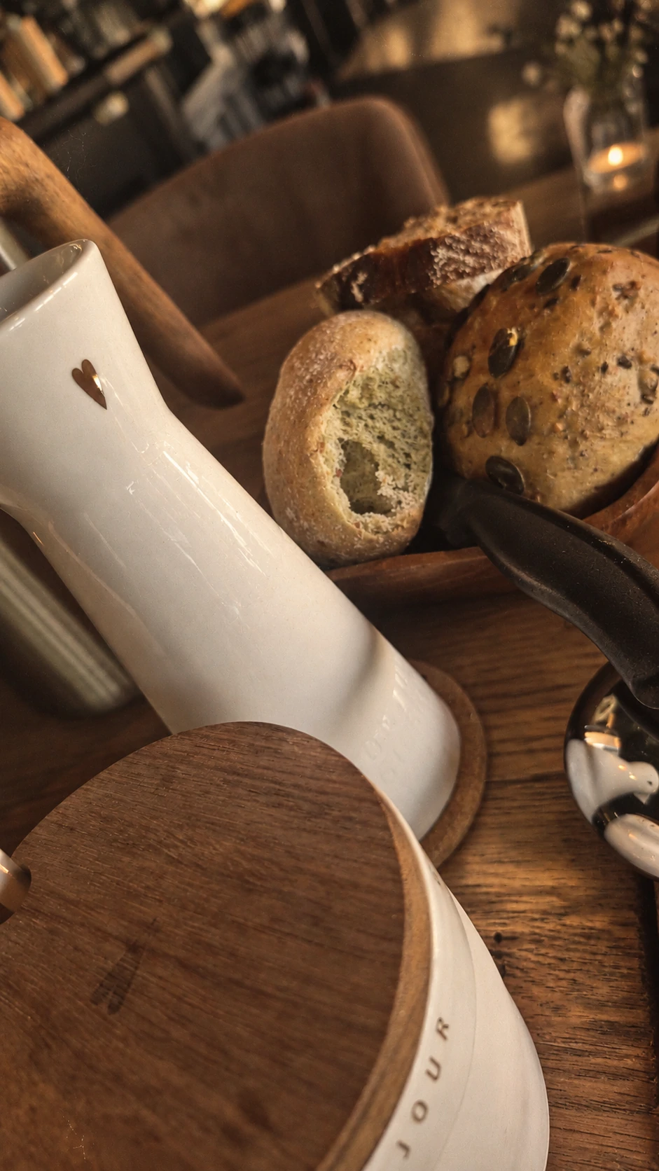 Kanne und Brot auf einem ruhig gedeckten Frühstückstisch