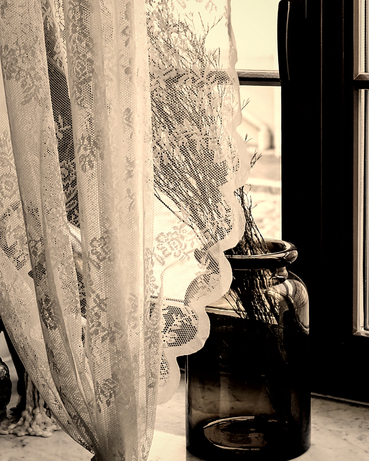 Spitzenvorhang und Glasvase am Fenster