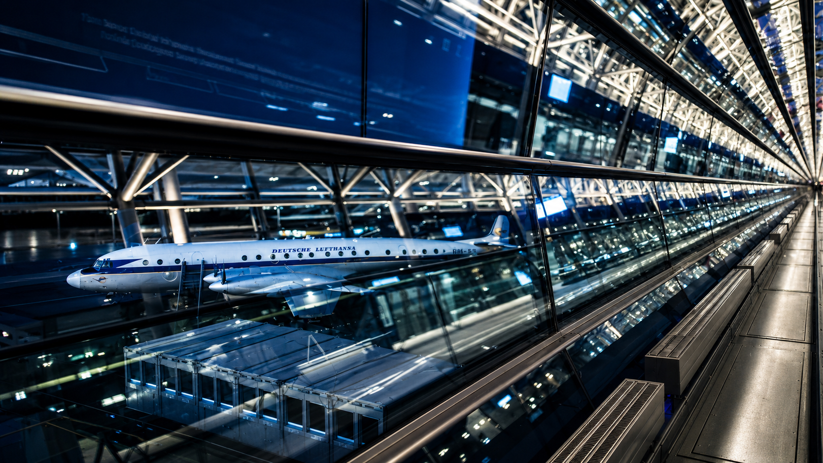 Flugzeug im gläsernen Terminal des Flughafens Leipzig mit starken Spiegelungen.