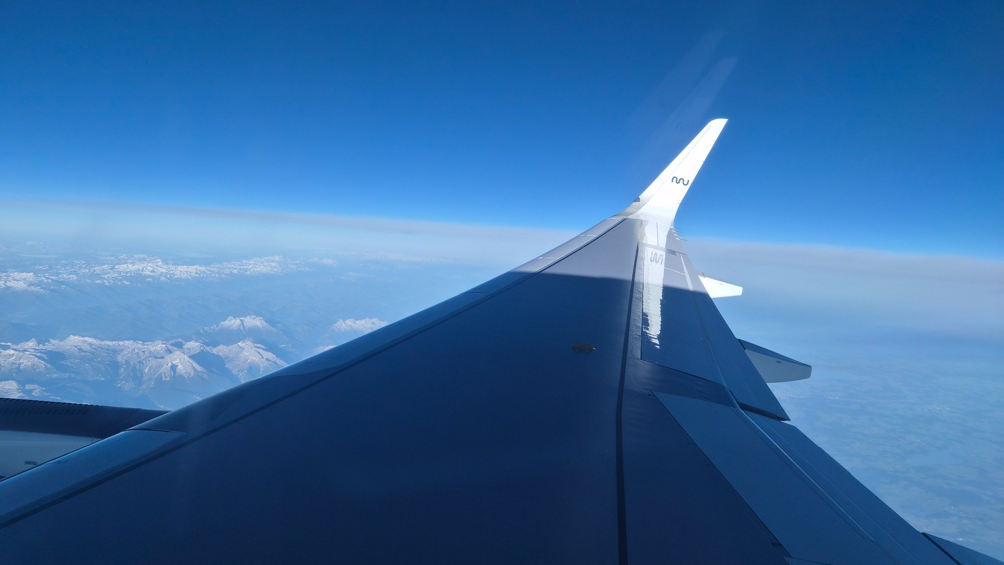 Blick aus dem Flugzeugfenster über Tragfläche und Gebirge.